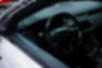 Luxury Range Rover interior with steering wheel, dashboard, and center console; sleek black cabin under soft light.