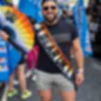 Man smiling with Mr Bear UK 2021 sash and holding a bear pride fan