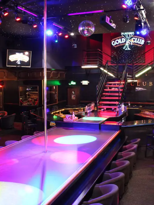 Interior view of The Gold Club with stage, pole, seating and lights.