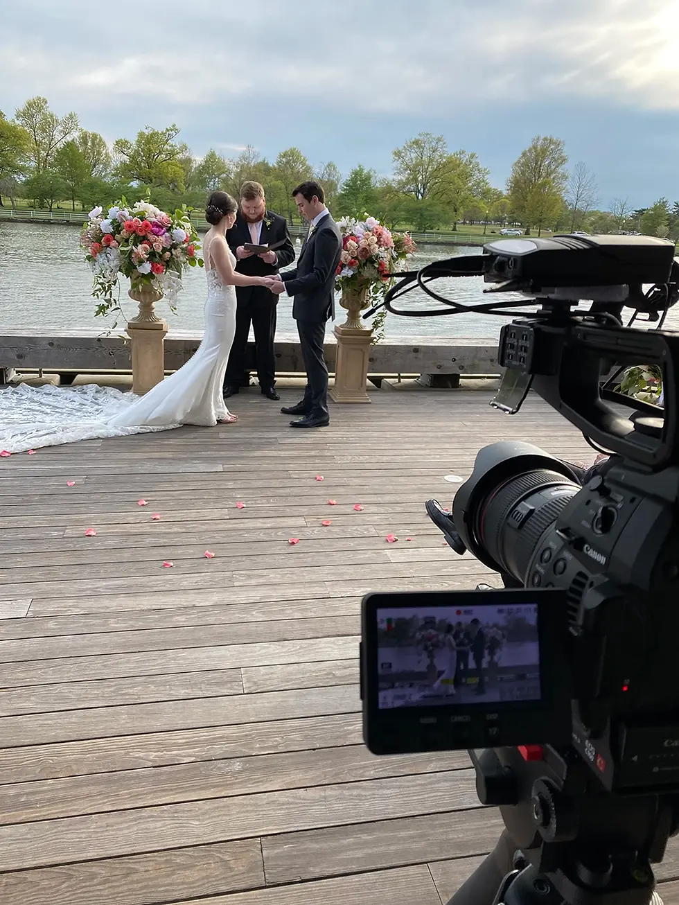 Videographer captures wedding couple exchanging vows on a beautiful waterfront deck.