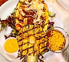 Grilled pineapple dish with shrimp, cheese, and sauces on a white plate.