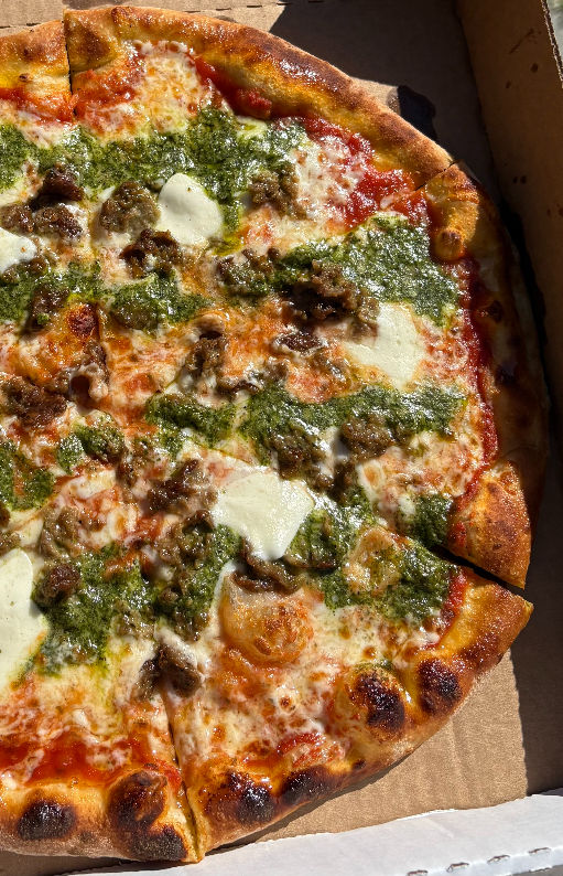 Delicious pizza with pesto and toppings; Timber Pizza close up view.
