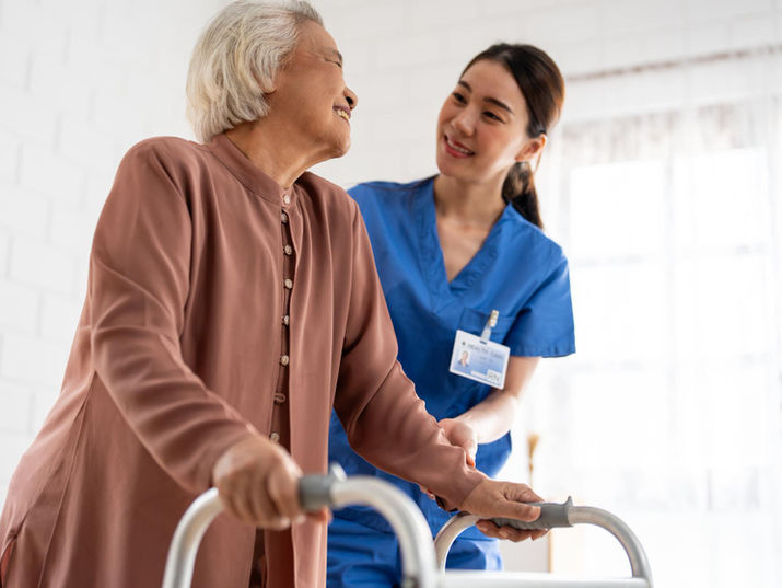 Elderly woman with walker and caregiver