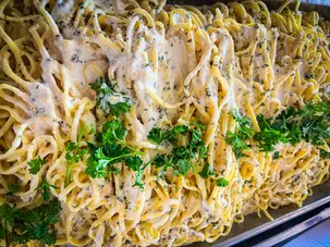 Large tray of pasta with creamy sauce and parsley