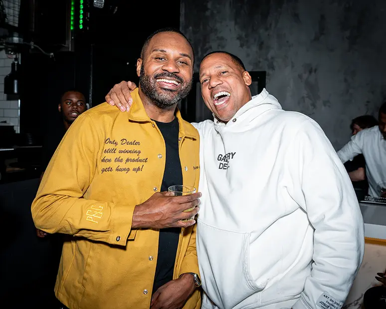 Two men smiling, wearing shirts that say 