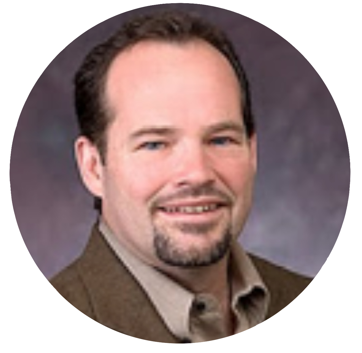 Smiling team member with goatee in brown blazer.