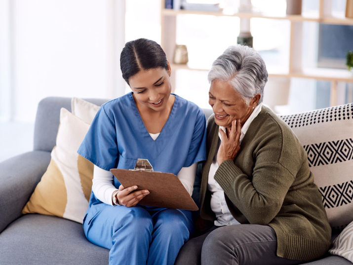 Female caregiver and senior woman reviewing clipboard.