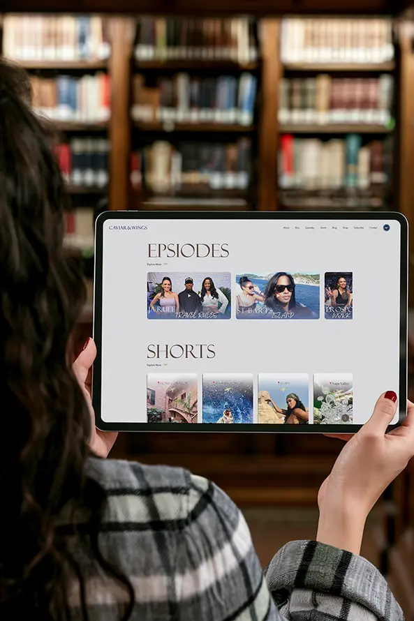 Person viewing "EPISODES" and "SHORTS" content on tablet, library bookshelves.