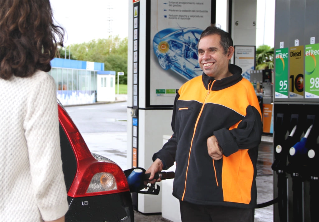 Smiling gas station attendant assisting a customer.