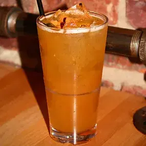 Tall glass of cocktail with garnishes, Booze, on a wooden table.