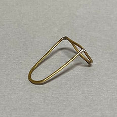 Angular brass ring with a geometric frame design on a grey background.