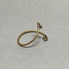 Minimal brass ring with curved ends, one featuring a small bead, displayed on a light gray background.