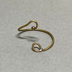 Open brass ring with one looped end and one curled end featuring a small bead, placed on a gray background.