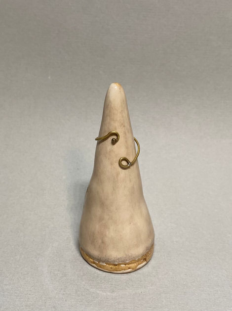 Open brass ring with curled ends displayed on a ceramic cone stand against a light gray background.