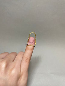 Brass arch-shaped ring worn on index finger, extending above the fingertip.