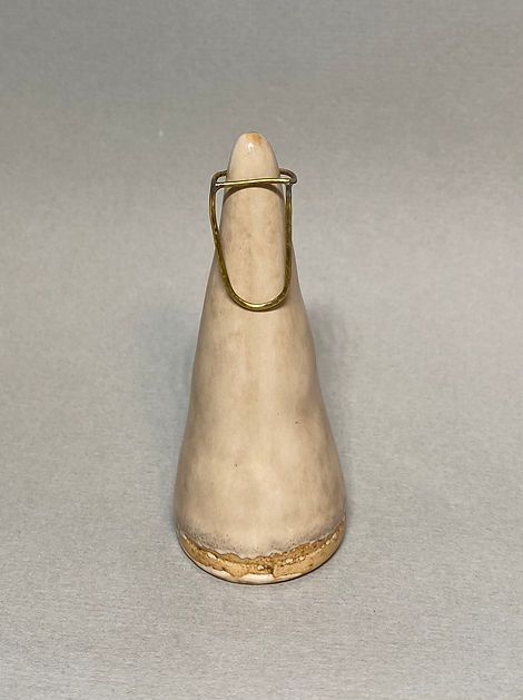 Oval-shaped brass ring displayed on a beige ceramic cone against a grey background.