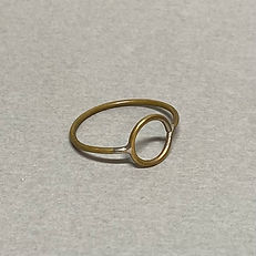 Brass ring with a flat circular center element, lying on a light gray surface.