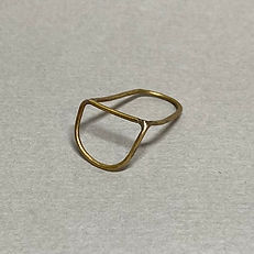 Brass ring with wide open oval shape resting on a light grey surface.