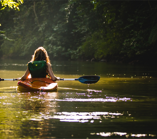A woman kayaking in a lake with trees in the background