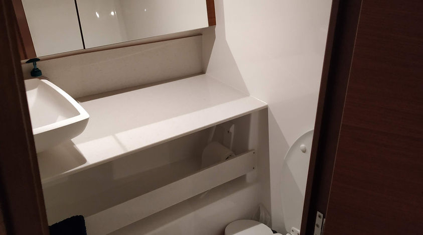 Small boat bathroom with toilet, sink, and mirror