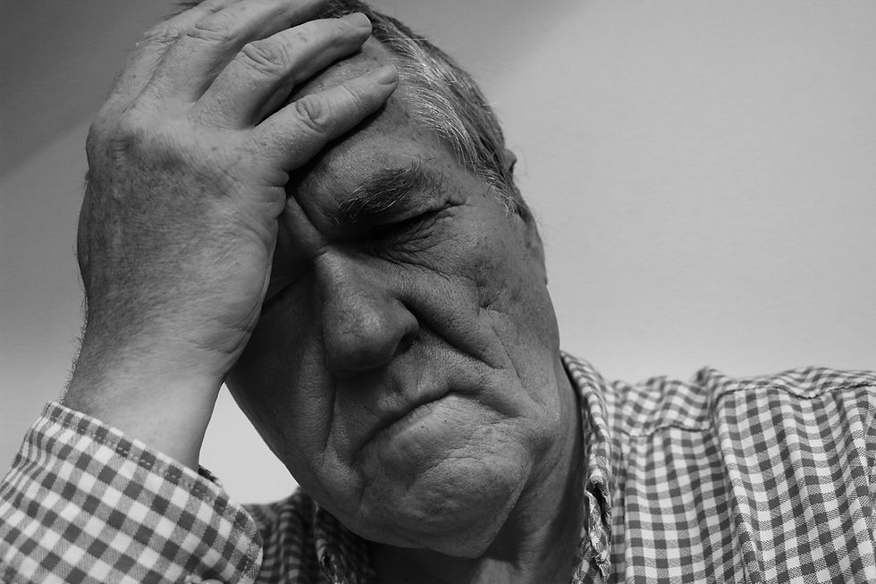 A man holding his head due to headache from post concussion syndrome.