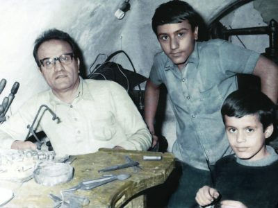 Vintage photo of Abraham Akcan and his two young sons, Isaac and John in his workshop, representing family heritage.