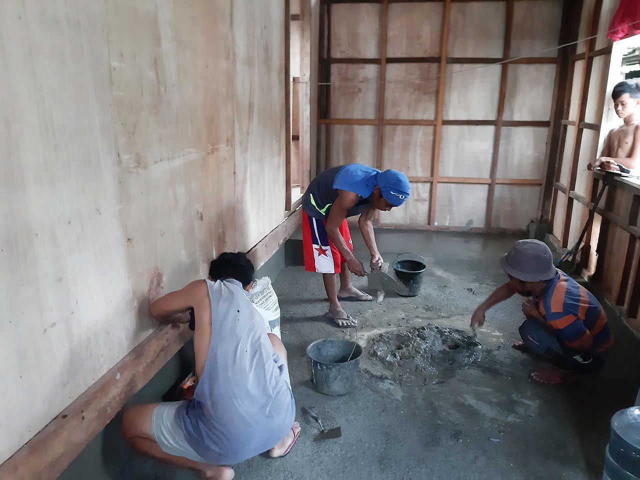 Abounding employee mixing cement for the new house of a Filipino family.