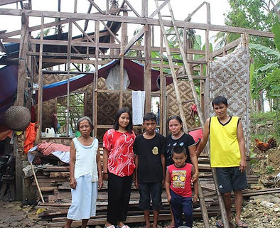 A family in the Philippines standing by their house which was damaged by Typhoon Odette