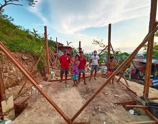 A Filipino family standing on the foundation for their new house