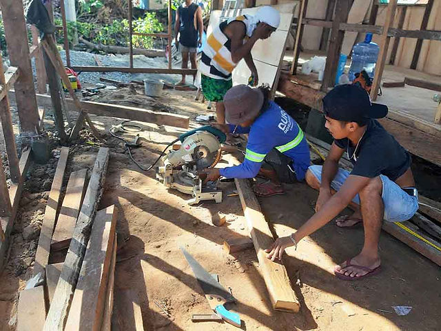 Abounding employee cutting wood for rebuilding new home for a Filipino family.