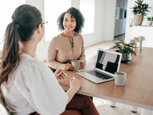 Dos compañeras de trabajo charlando en su oficina.