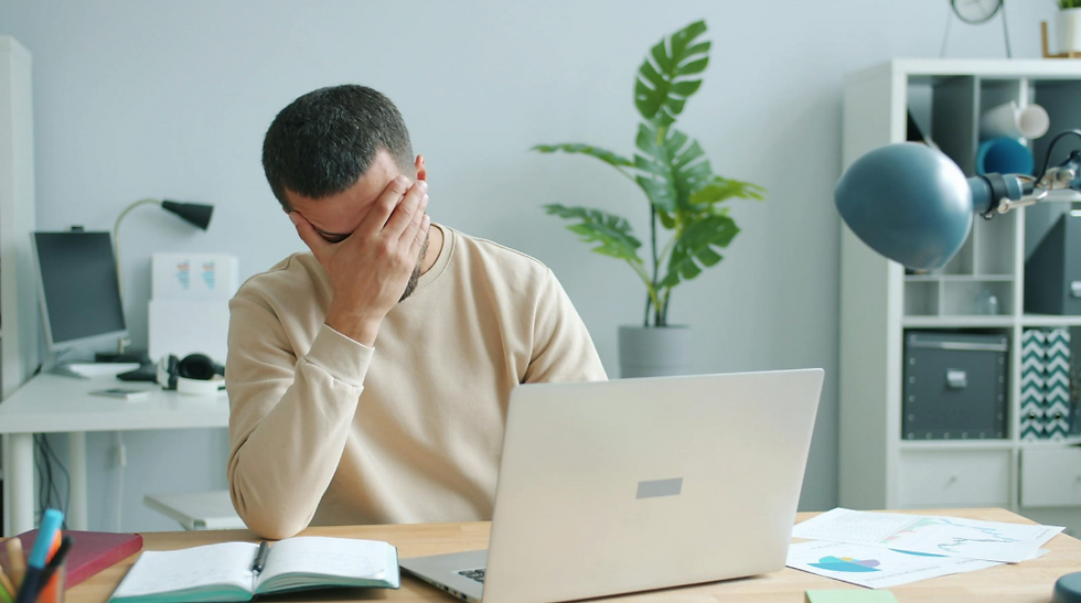 Un trabajador mostrando signos de estrés frente a su computadora.