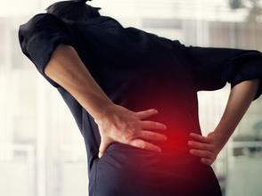 Persona adulta sosteniéndose la espalda baja en señal de dolor.