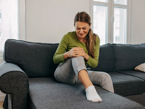 Mujer sosteniéndose la rodilla en señal de dolor