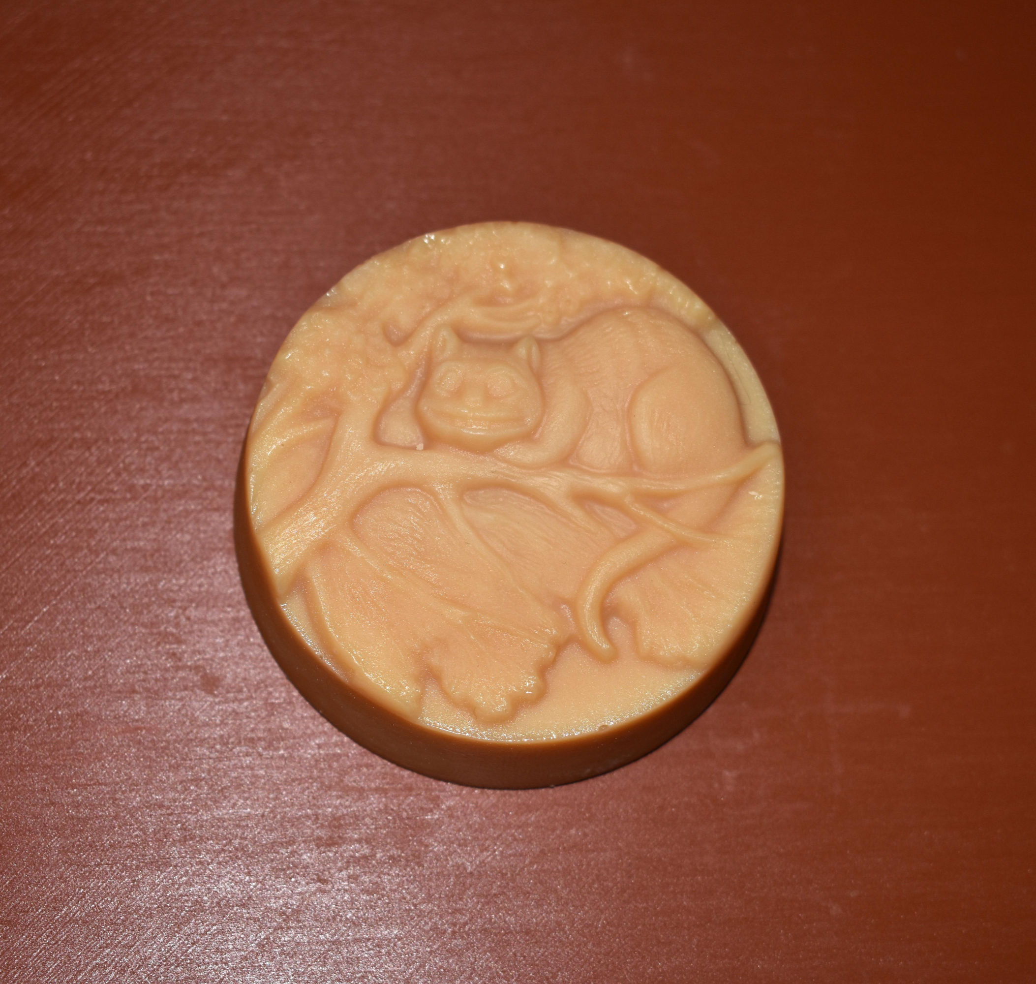 A puck of soap with the Cheshire Cat perched in a tree.
