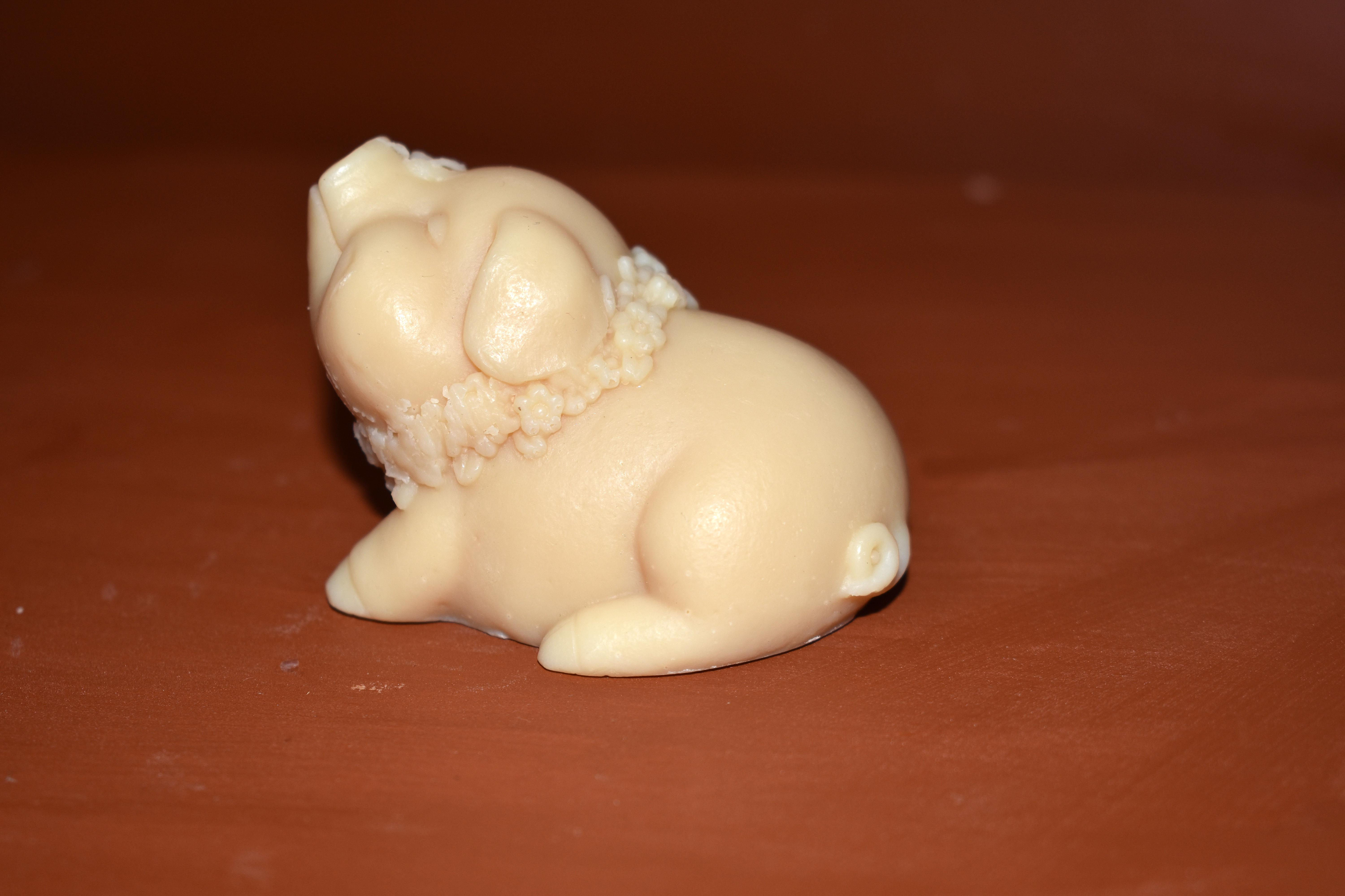 A side image of a pig shaped soap, balancing a butterfly.
