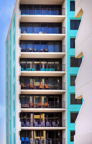 The balconies of a hotel furnished with colorful adirondack chairs