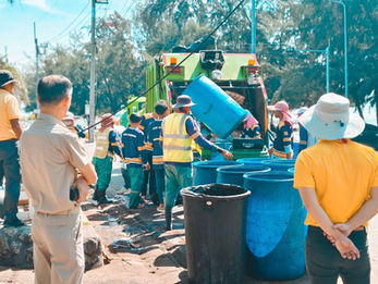 พนักงานเก็บขยะกำลังทิ้งถังขยะลงในรถบรรทุกสีเขียว ทำความสะอาดชายหาด นคร ระยอง