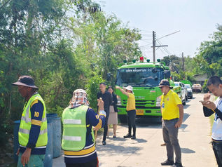 พนักงานยืนข้างรถบรรทุกสีเขียวในโครงการ บริษัท คลีน มหานคร จำกัด นคร ระยอง