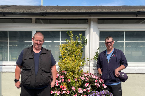 Ben and Ben, from the Aldingbourne Trust, stand beside large flower beds that they plant and maintain.