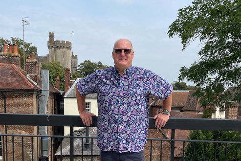 Mark stands on the roof terrace of the Arundel Town Hall, with Arundel Castle in the background.