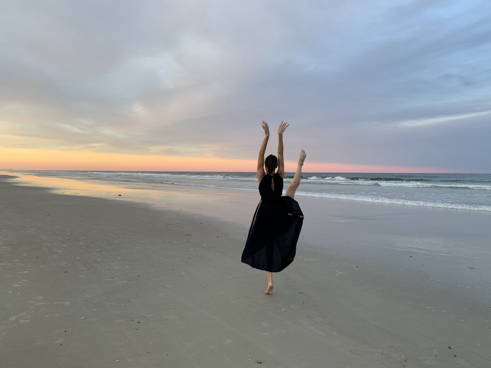 Client joyfully dancing on the beach at sunrise, embodying the strength, flexibility, and confidence gained through Pilates training at Encore Pilates in Gainesville, FL. A celebration of wellness and mindful movement.