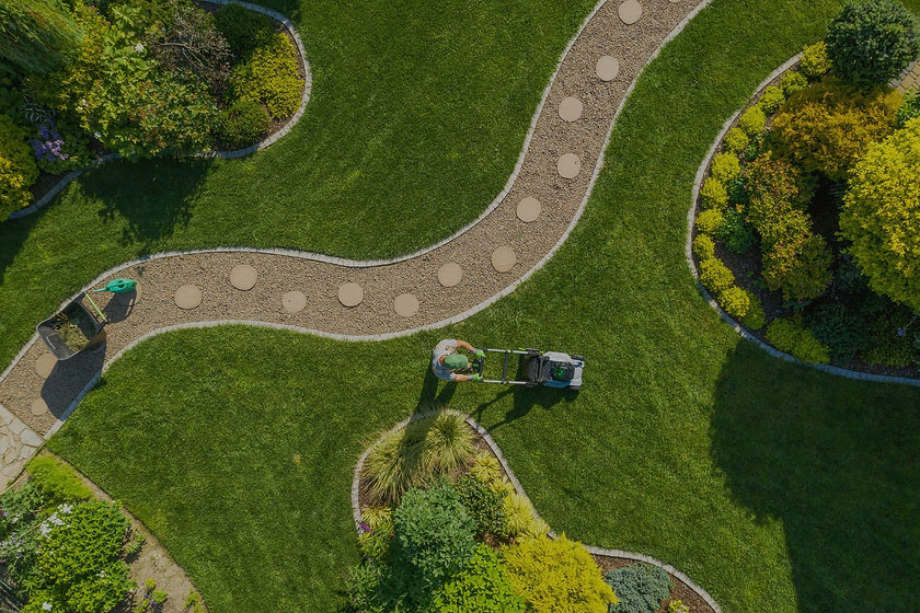 ariel view of professional lawn care worker mowing the lawn in a suburban home