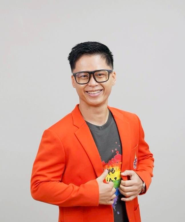 Smiling man with glasses and orange jacket