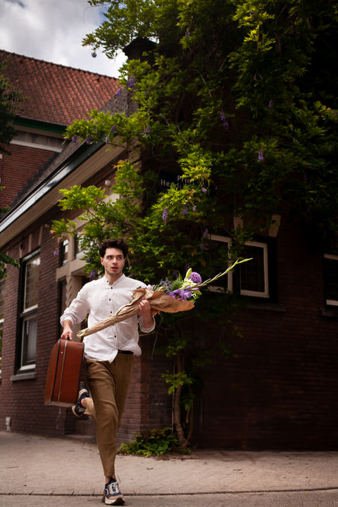 Boy running while holding a bouquet of flowers and an old suitcase