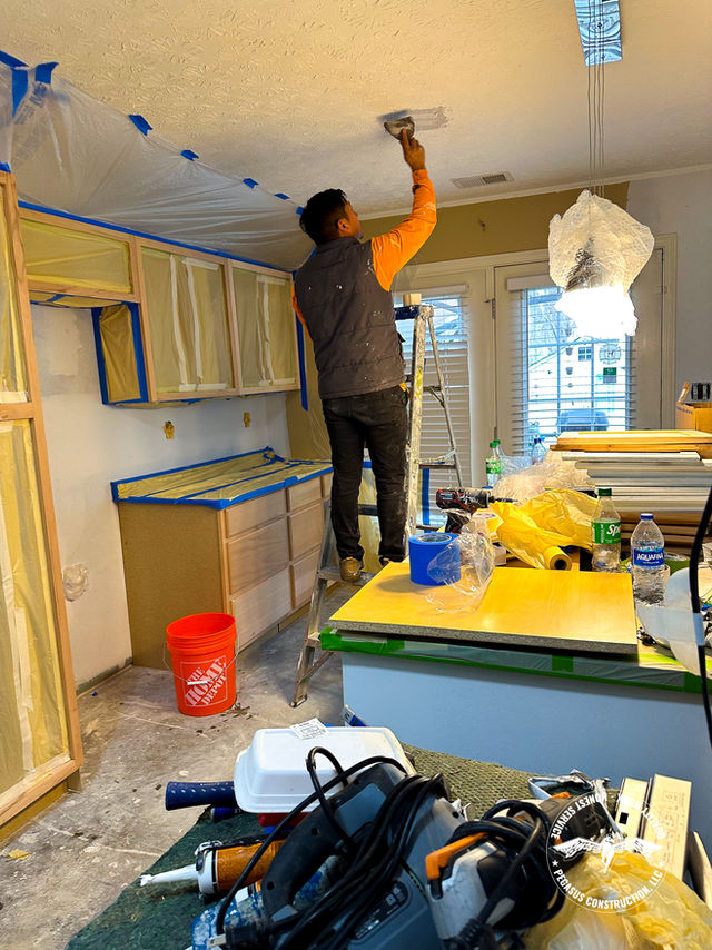 This is an image where you can see an employee working on cabinets and the kitchen tops.