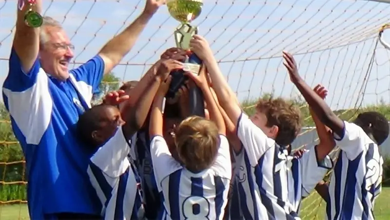 Soccer players lifting a trophy.