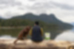 Pet owner and dog sitting on a log overlooking the water, with Red Dog Blue Kat Everyday Raw Anywhere trail-friendly dog food
