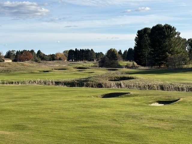 "Fall view of The Gailes golf course at Lakewood Shores, featuring green fairways, sand bunkers, and autumn trees under a partly cloudy sky.