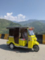 A bright yellow rickshaw in Pakistan with mountains in the background